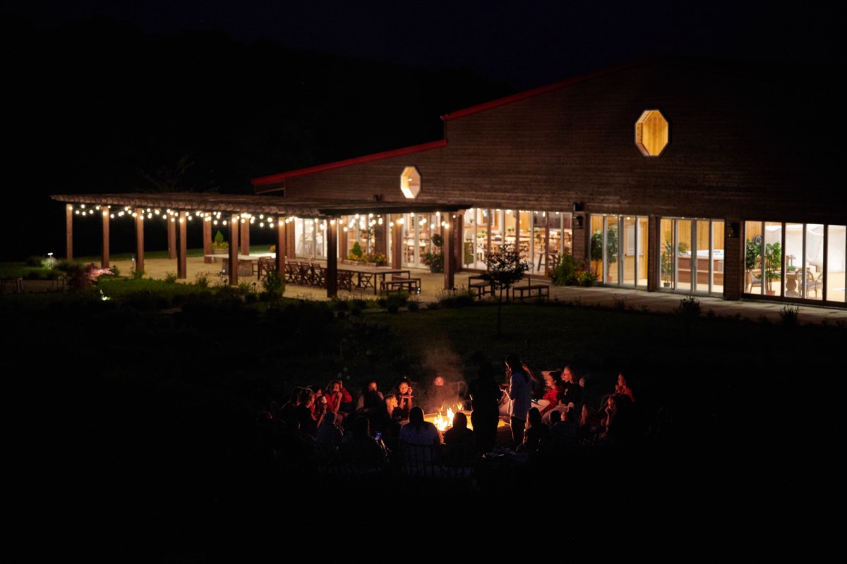 Guests around the evening fire circle outside the lit dining hall