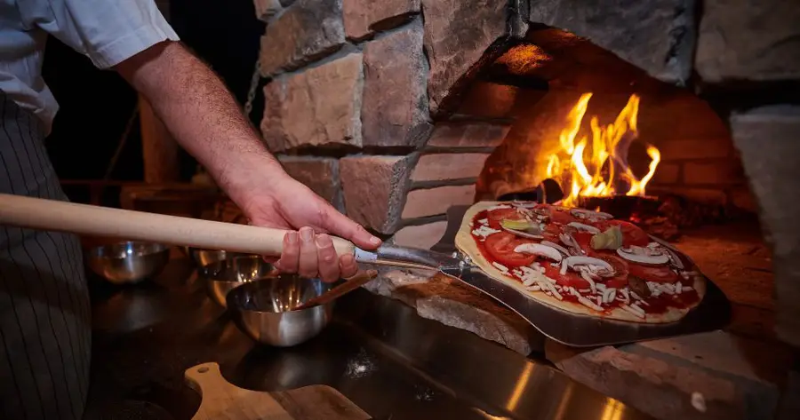 A pizza going into the wood-stone oven