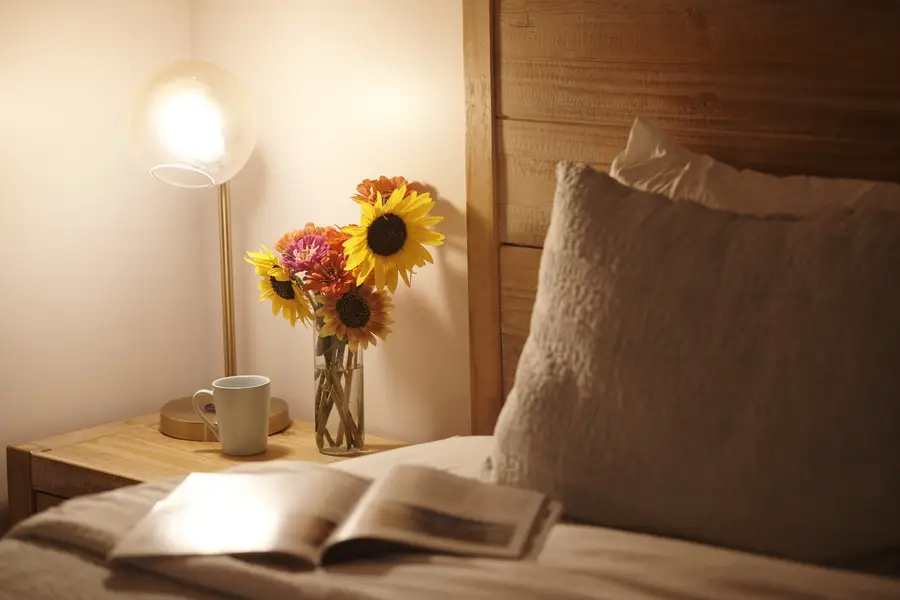A warm bedside lamp, sunflowers and an open book