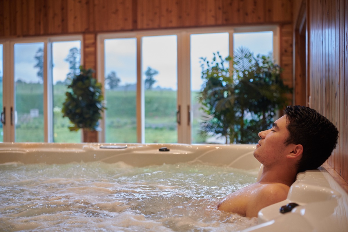 A guest resting in the jacuzzi by the windows