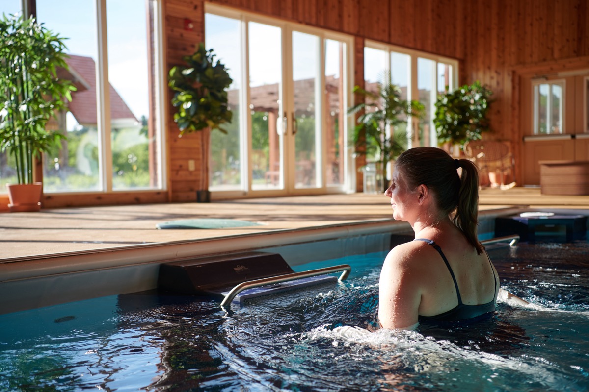 A guest in the endless-stream hydrotherapy pool, mountains through the windows
